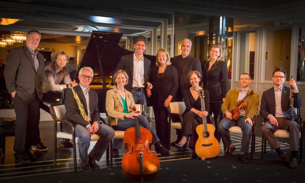 The Spiritu ensemble together with their instruments in warm light.